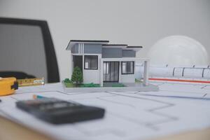 A small model house sits on top of a desk photo