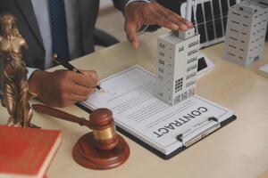 A man signing a contract with a model of a building photo