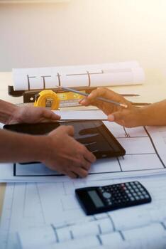 Two people working on a project with a tablet and calculator photo
