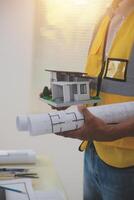 A man holding a blueprint and a model of a house photo