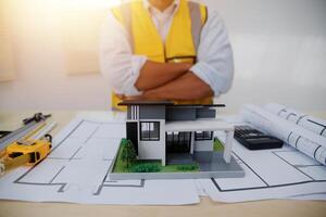 A man in a yellow vest and hard hat standing in front of a model house photo