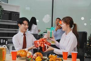 A man and woman are sitting at a table with a christmas tree and presents photo