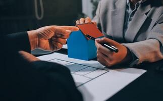 Two people are holding a house model on a table photo