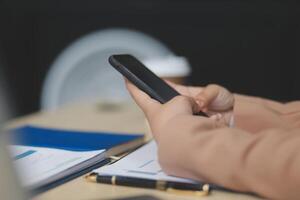 A person holding a cell phone while sitting at a desk photo