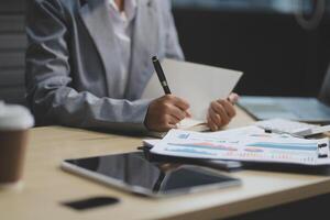 A businesswoman is writing on a notepad while sitting at a desk photo