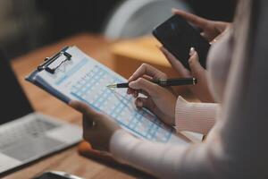 A woman writing on a clipboard with a pen and a smartphone photo