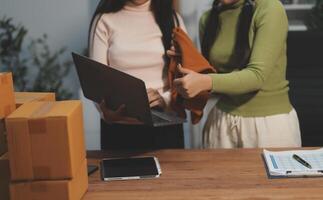 Two women standing in front of a laptop and boxes photo