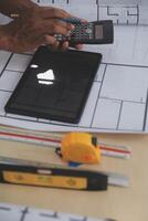 A person using a calculator and a tablet on a table photo