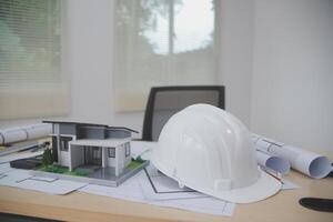A hard hat and model of a house on a desk photo