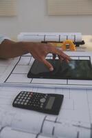A person using a tablet on a table with construction plans photo