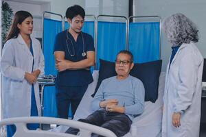 A group of doctors and nurses standing around a patient in a hospital bed photo