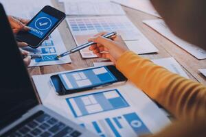 A person is using a smartphone and laptop to work on a website photo
