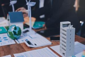 A table with a model of a building and papers photo