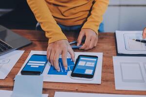 A person is using a smartphone and laptop on a table photo