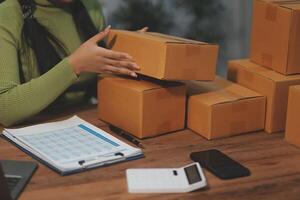A woman is packing boxes on a desk with a laptop photo