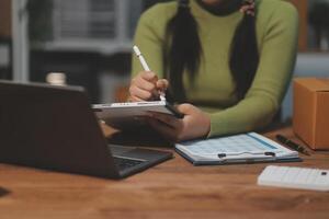 A woman is writing on a piece of paper while sitting at a desk photo