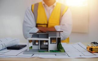 A man in a yellow vest and hard hat standing in front of a model house photo