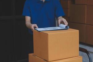 A man is holding a piece of paper while standing next to boxes photo