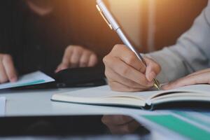 Businessman writing in notebook with pen and paper photo