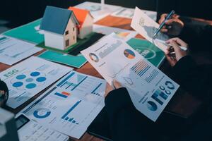 Businessman looking at financial reports on desk with house model photo