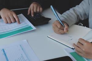 Two people are working on paperwork at a table photo