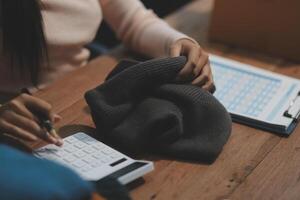 A woman is using a calculator to calculate the cost of a hat photo