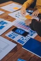 A person is working on a design project with a laptop and a phone photo
