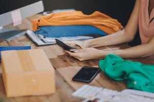 A woman is using her cell phone while sitting at a desk with a computer and other items photo