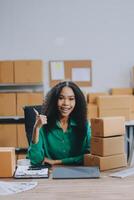 A woman sitting at a desk with boxes and a laptop photo