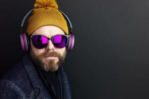 Stylish man wearing headphones and sunglasses against a dark background photo