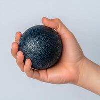 Burnout recovery stress concept. A hand holding a textured black ball against a light background. photo