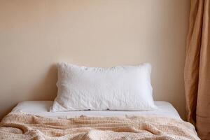 Burnout recovery mental concept. Cozy bed with a white pillow and textured blanket against a beige wall. photo
