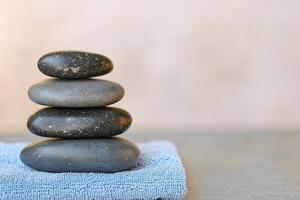 Burnout recovery stress concept. Stacked black stones on a blue towel, symbolizing tranquility and balance. photo
