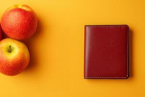 Cost of living and income concept. Red wallet and two apples on a vibrant yellow background. photo