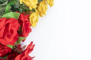 Vibrant red and yellow artificial roses on a bright white background with copy space photo