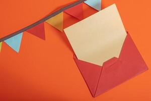 Red envelope with blank letter and festive bunting on orange background for Valentine's Day. photo