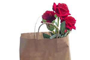 Beautiful red roses in a brown paper bag on a white background photo