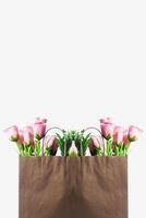 Fresh pink flowers in a brown paper bag with a white background photo