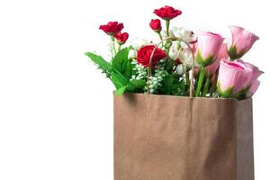 Bouquet of artificial flowers in a brown paper bag on a white background, copy space photo