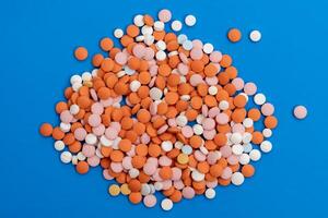 Pile of multicolored pills on blue background photo