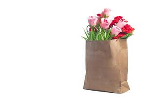 Beautiful flower bouquet in a brown paper bag on a white background with copy space. photo
