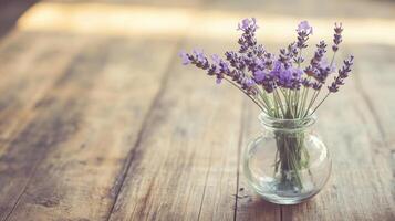Lavender blooms in a glass vase on a rustic wooden table with sunlight shining through a nearby window photo