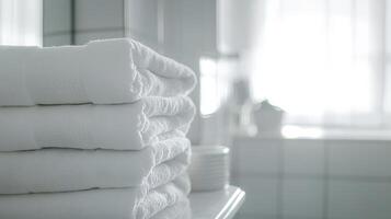 Soft white towels neatly stacked on a bathroom shelf with natural light illuminating the space in a serene morning setting photo