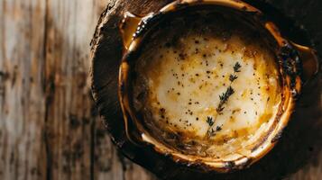 Warm and creamy baked cheese topped with fresh herbs in a rustic serving dish on a wooden table photo