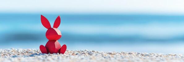red paper bunny cutout sitting on the beach with the ocean in the background photo