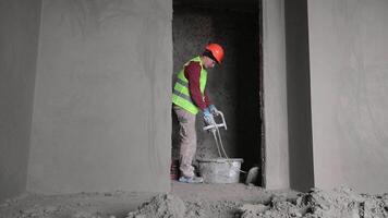 Worker mixing construction materials on renovation site, Construction worker using a mixer to prepare materials indoors video