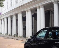 A black car parked in front of a building with white pillars photo