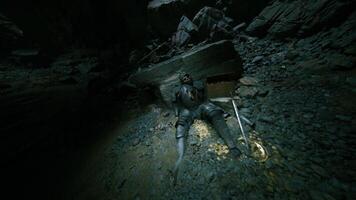 Fallen knight rests in a dark cave surrounded by ancient rocks and shadows video