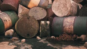 Old rusted barrels piled against a weathered wall in an abandoned location video