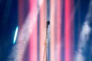 A concert microphone against a background of multicolored light and smoke from the stage spotlights. photo
